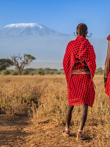 Warriors from Maasai Tribe standing in front of Mount Kilimanjaro in Kenya