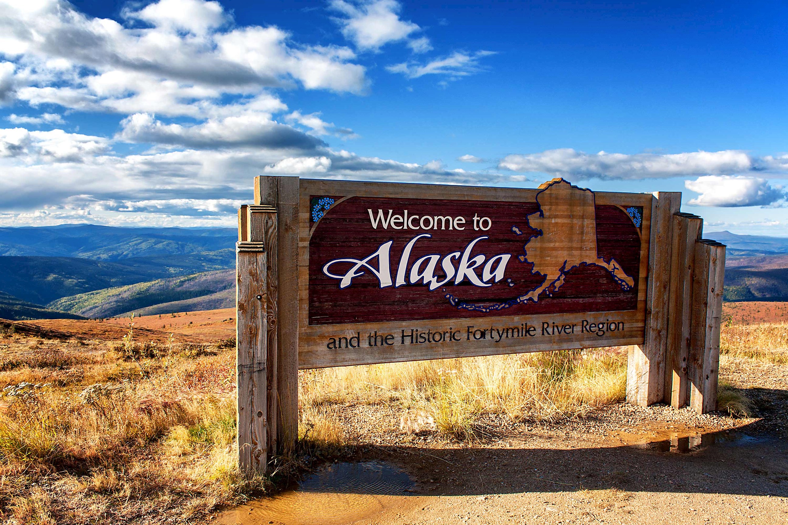 A Welcome to Alaska sign on a hill