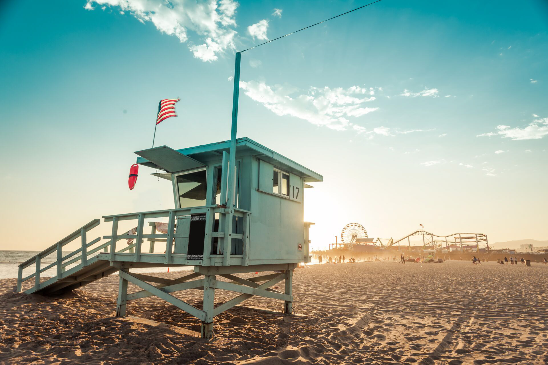A lifeguard tower on the beach with a flag on it