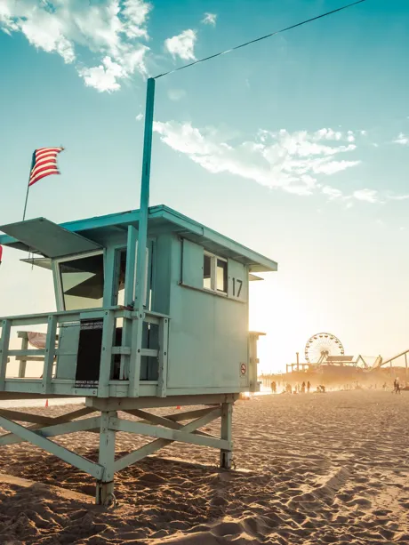 A lifeguard tower on the beach with a flag on it