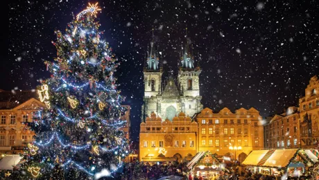 Decorated Christmas Tree and Tyn Church against sky during snowfall at night
