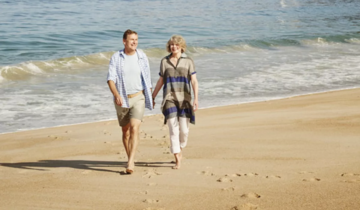 A man and a woman walking on Nazare Beach in Portugal