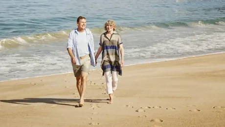 A man and a woman walking on Nazare Beach in Portugal