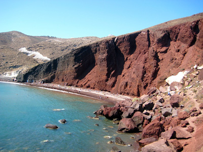 The sloped rust-coloured hillside of popular Red Beach in Santorini, Greece.