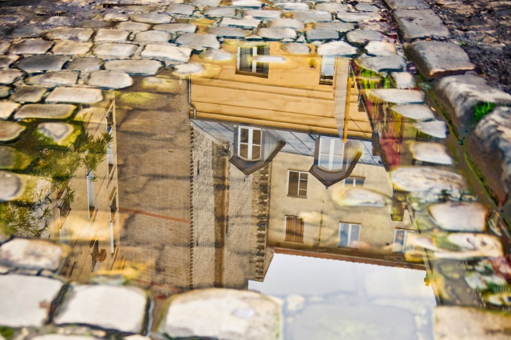 Reflection of a Parisian building in a puddle on cobblestones