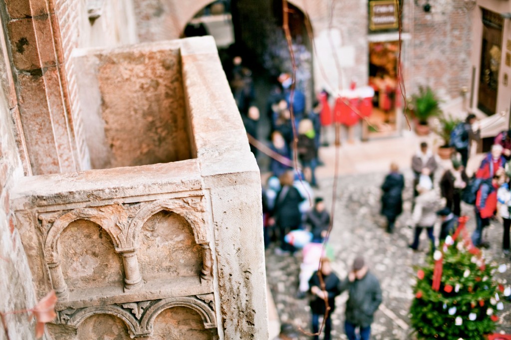 Closeup angle of Juliet's balcony in Verona, with tourists visible on the ground beneath