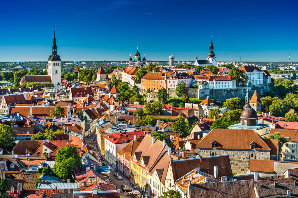 Landscape image of Tallinn, Estonia, can see the tops of buildings. Blue skies above.