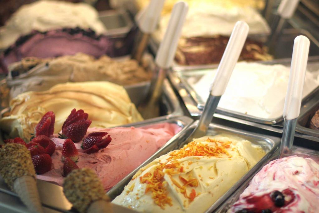 A close-up of multiple gelato flavors, resting in a gelateria case.