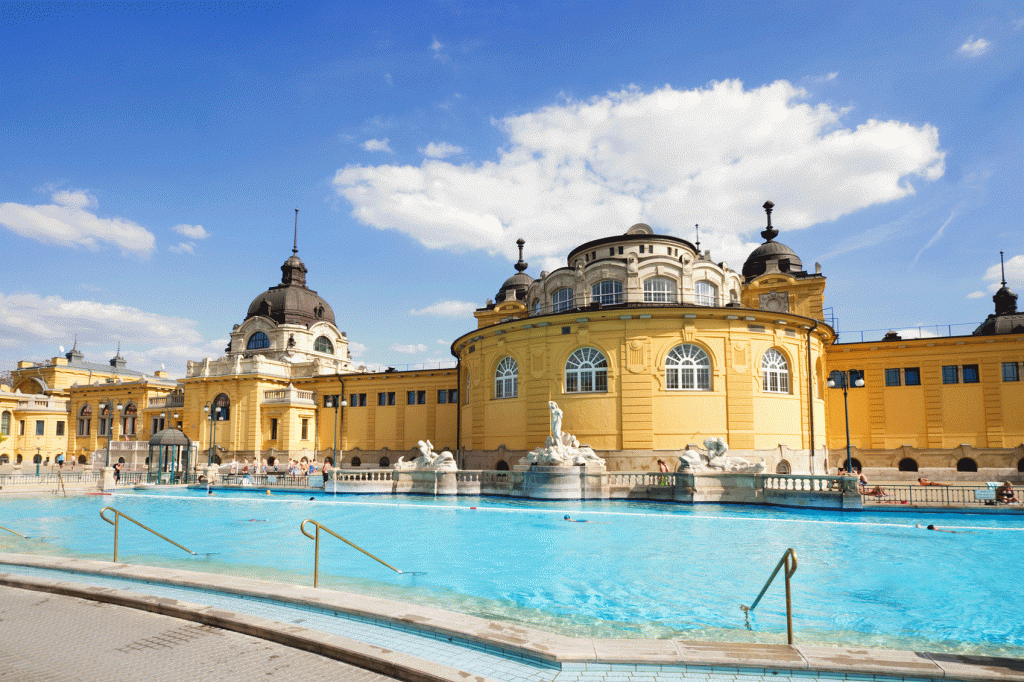 Széchenyi thermal bath: yellow ornate building with a bright blue pool in front 