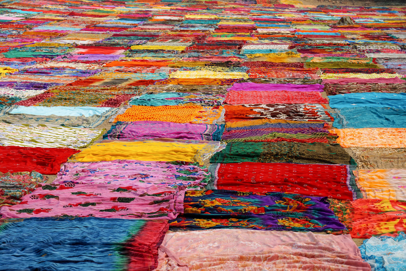 Colourful sheets drying on the ground.