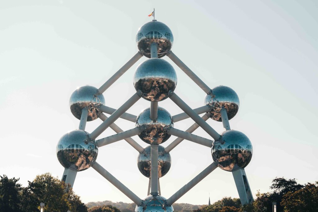 The Atomium in Brussels, Belgium, a futuristic structure of giant silver spheres connected by tubes, reflecting sunlight against a clear blue sky. This is a European landmark.