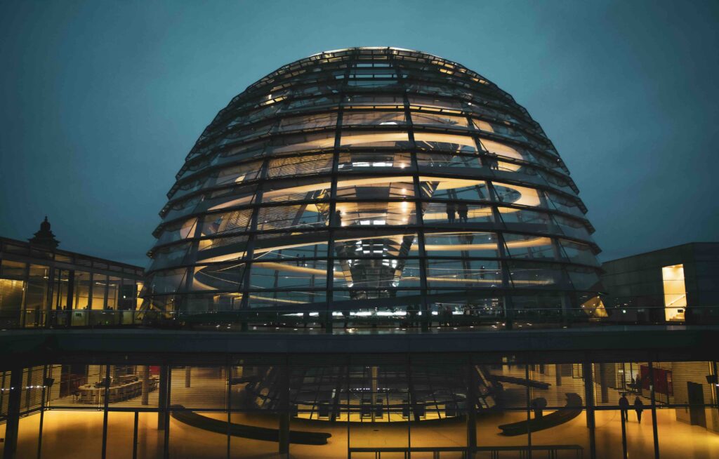 The Reichstag building in Berlin, Germany, with its neoclassical façade and modern glass dome under a dark night sky.