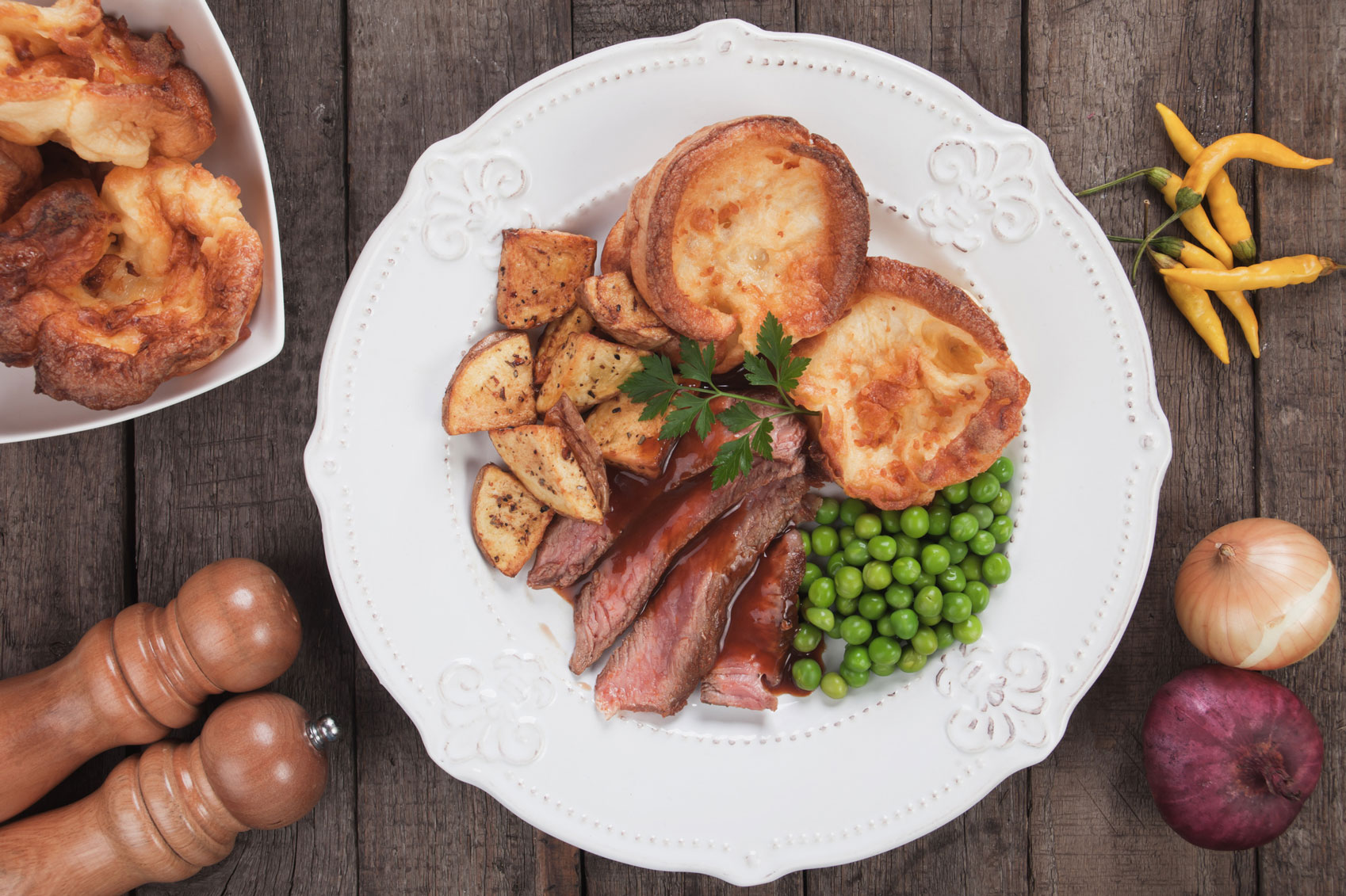 A plate of roast beef, yorkshire puddings, vegetables and gravy