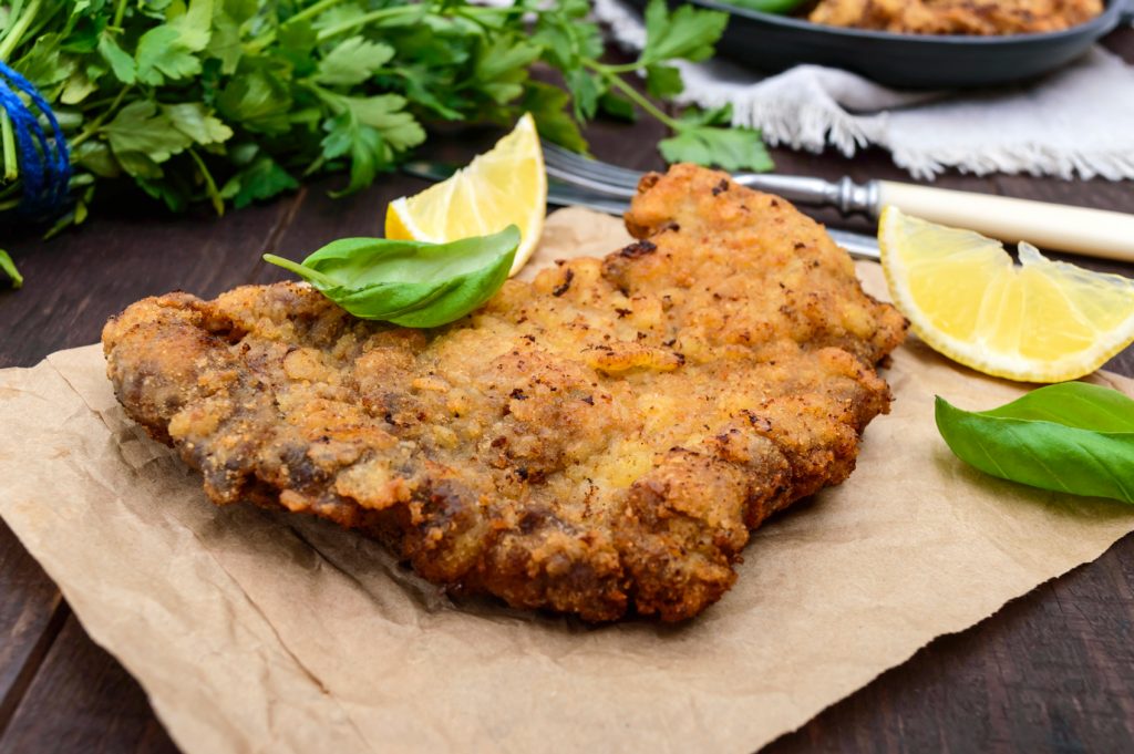 chicken schnitzel with lemon wedges on a brown paper.