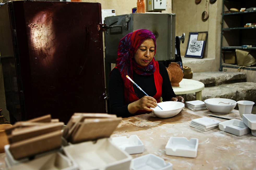 A woman painting a bowl at the Iraq Al Amir