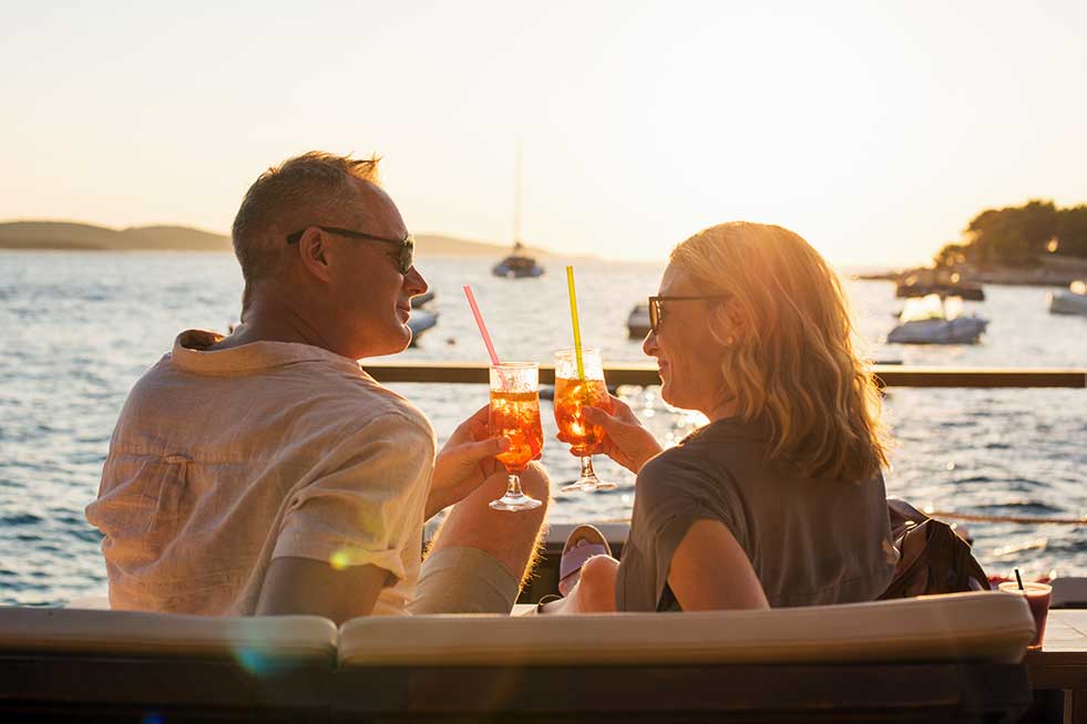 couple living their travel dreams toasting at sunset in Europe on boat

