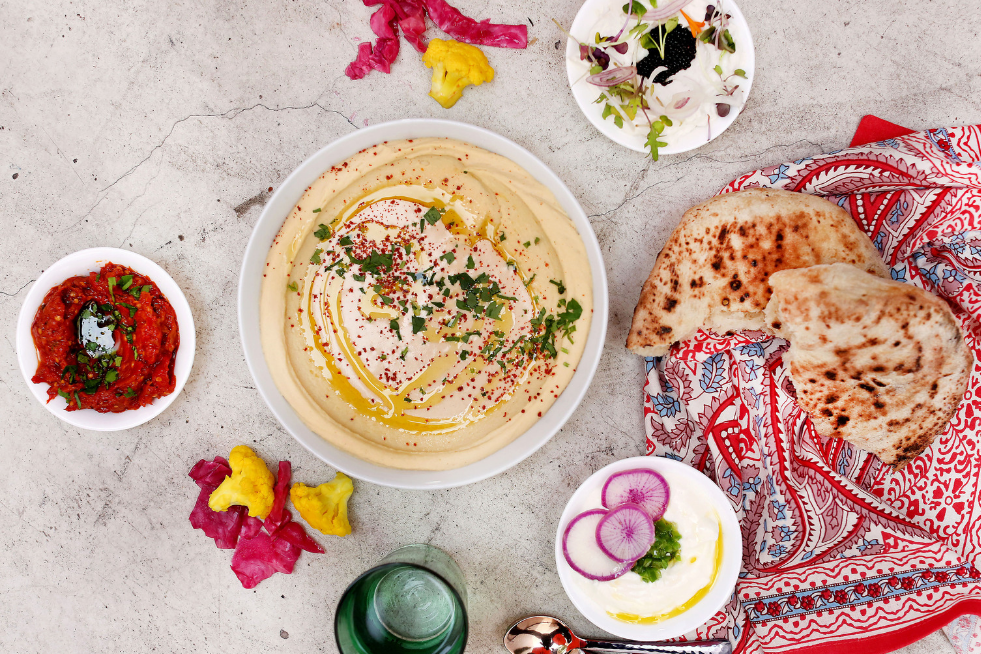 Top-down image of a bowl of hummus with accompaniments