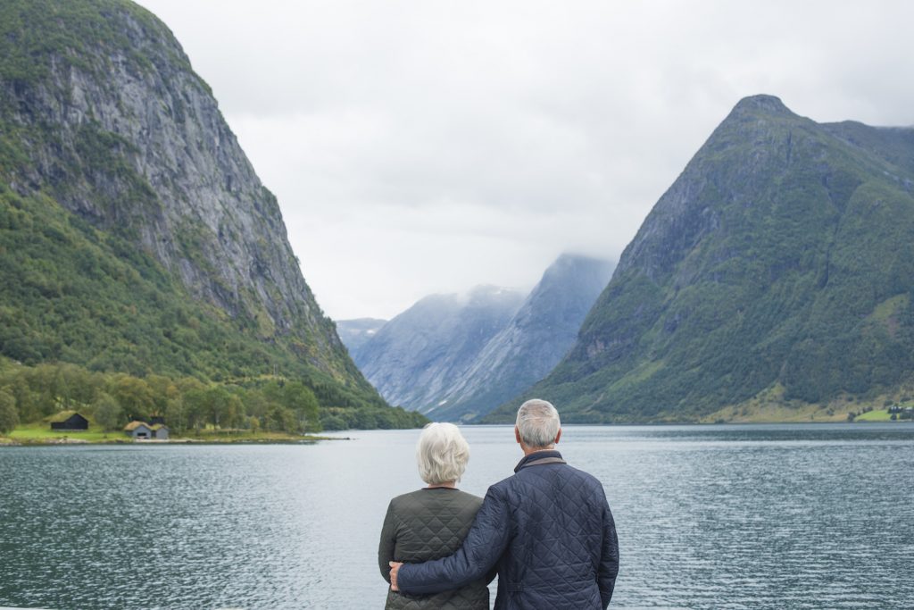 older couple standing with arms around each other by lake in Norway