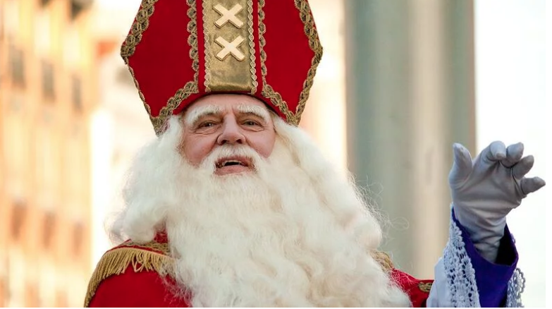 A man dressed as Santa is waving his hand in the air, embodying the spirit of St. Nicholas Day.