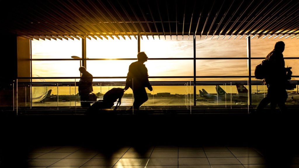 Silhouettes of people walking through an airport, maybe some are frequent flyers.