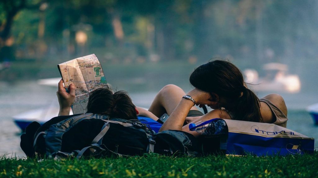 couple reading map in park travel safety