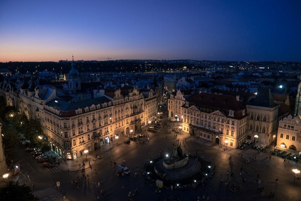 Birds-eye view of a square in Prague, buildings around the square and statue in the middle.