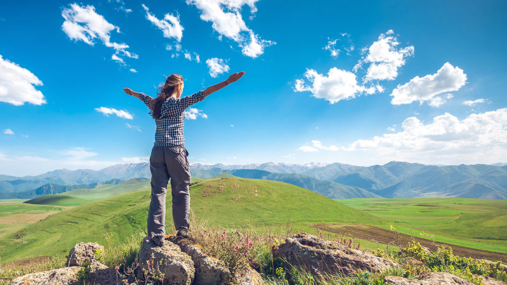 Woman with raising hands on a hill