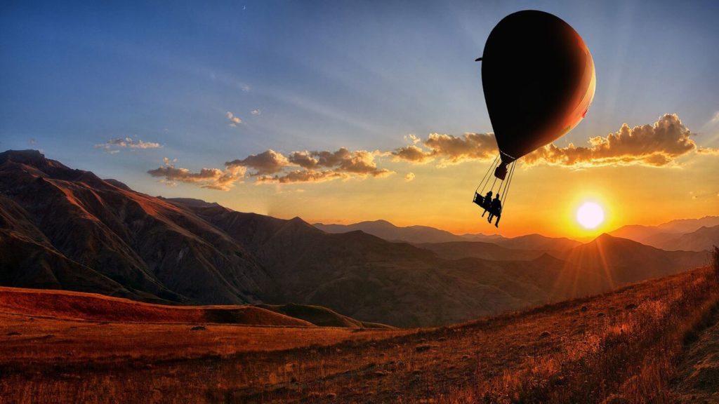 A hot air balloon soaring over the mountains during sunset, providing a unique travel experience.