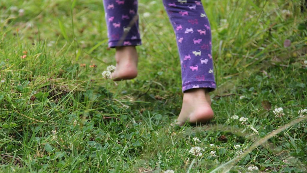 child running barefoot through grass