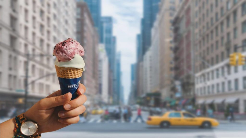 hand holding ice cream cone on New York city street summer in New York city