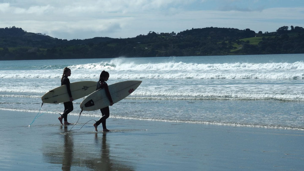 two surfers at the beach New Zealand laidback lifestyle
