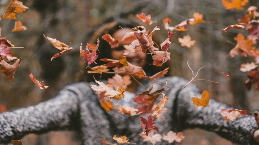 woman throwing autumn leaves reconnect with nature