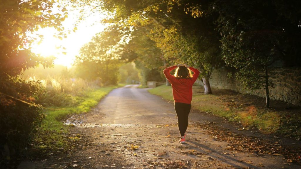 adult walking through forest trail at sunset