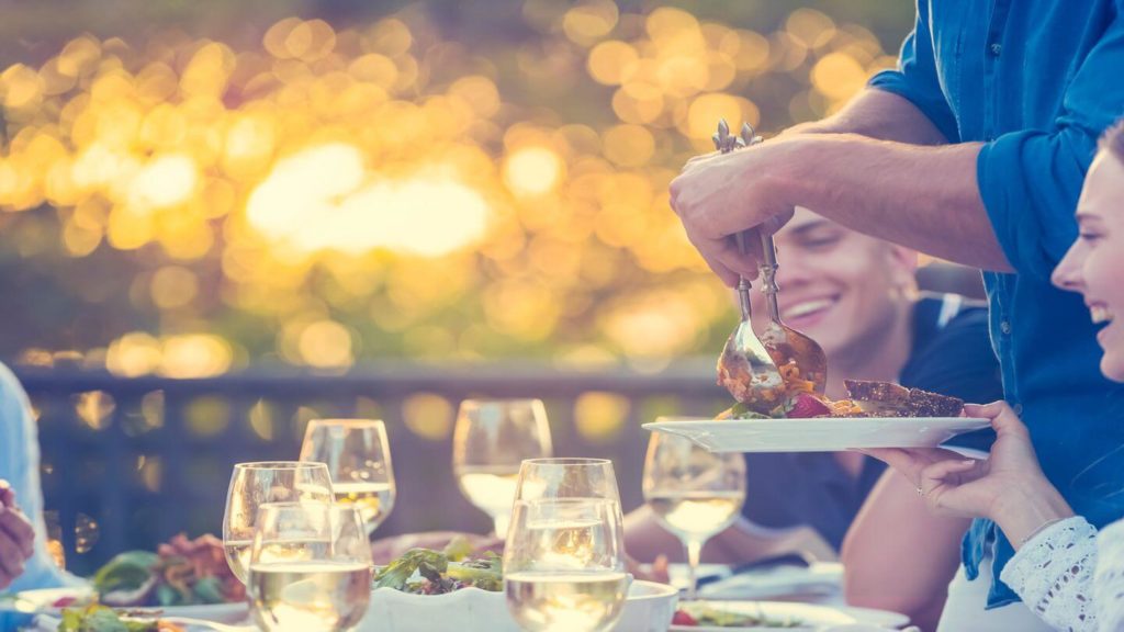 people enjoying a meal outside with wine glasses