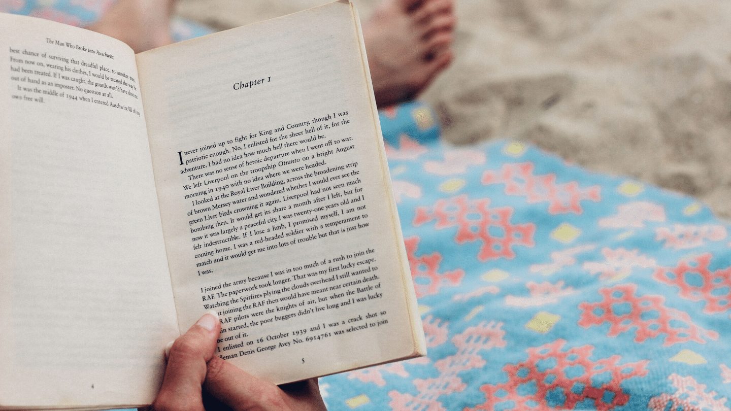Person holding an open book on the beach