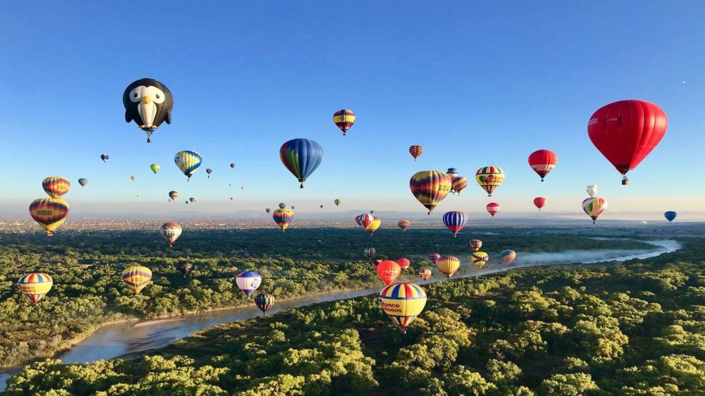 Experience the serene beauty of hot air balloons floating over a river during a fall getaway.