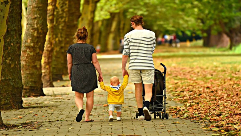 parents and baby walking through a park