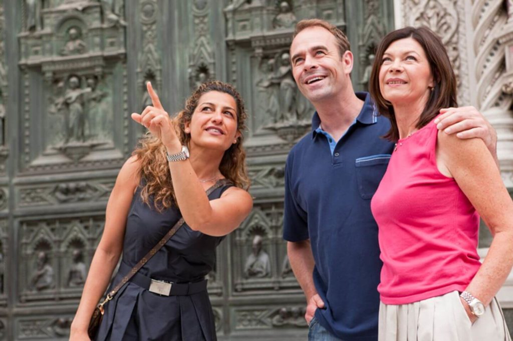 A small group of people standing in front of an ornate door, enjoying the benefits of travelling together.