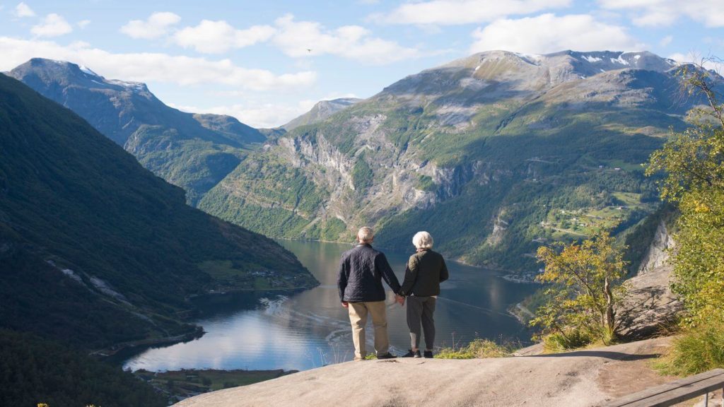 couple holding hands on a mountain fjord viewpoint