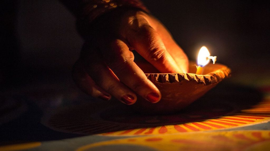 hand lighting a candle for Diwali celebrations