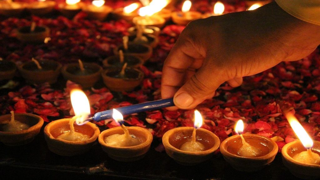 A hand lighting candles for Diwali