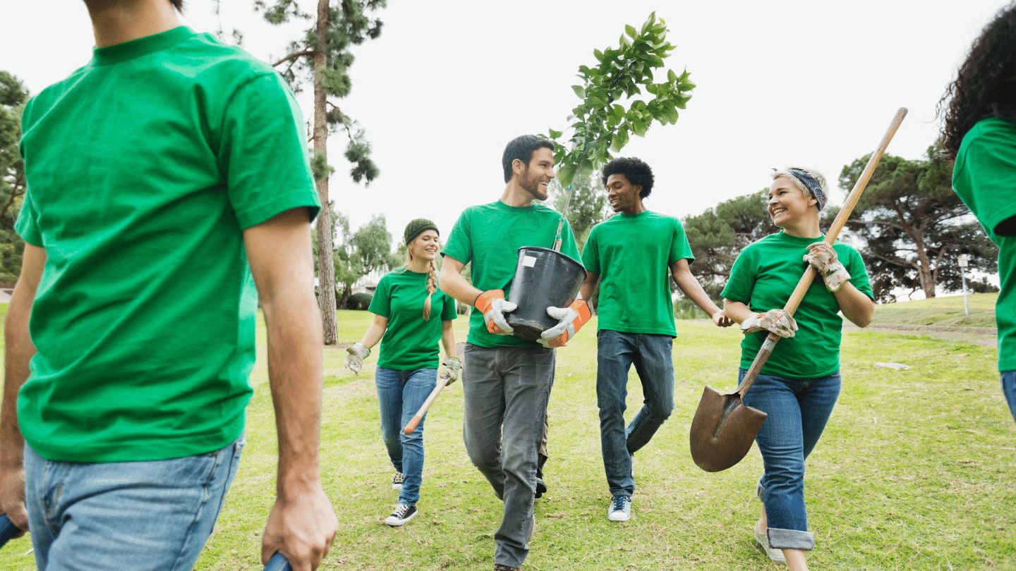 Group of people in green t-shirts planting trees - responsible travel