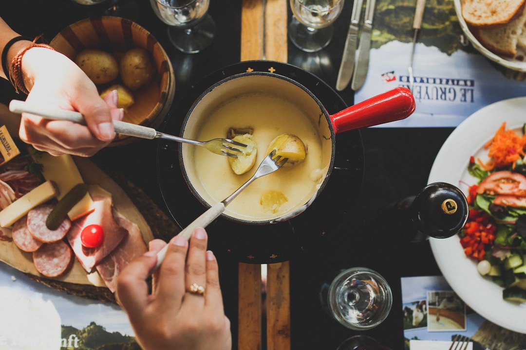 potatoes being dipped in cheese fondue