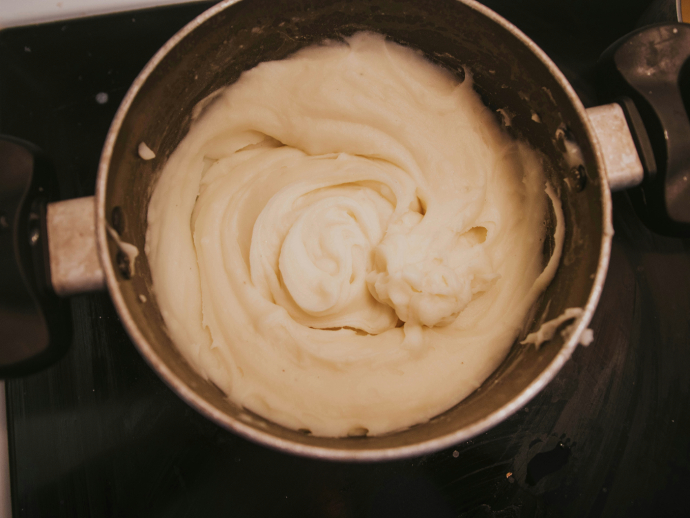A pot of whipped mashed potatoes set on a stove top.