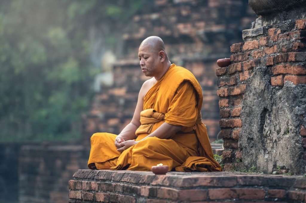 buddhist monk meditating in orange robes Thailand