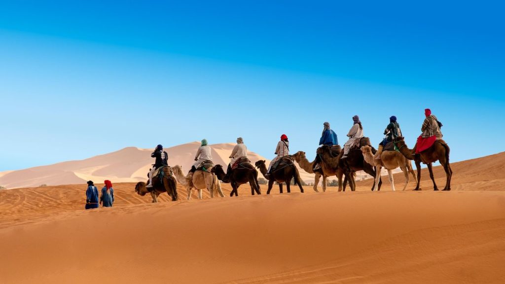 people riding camels through the Sahara Desert winter in Morocco