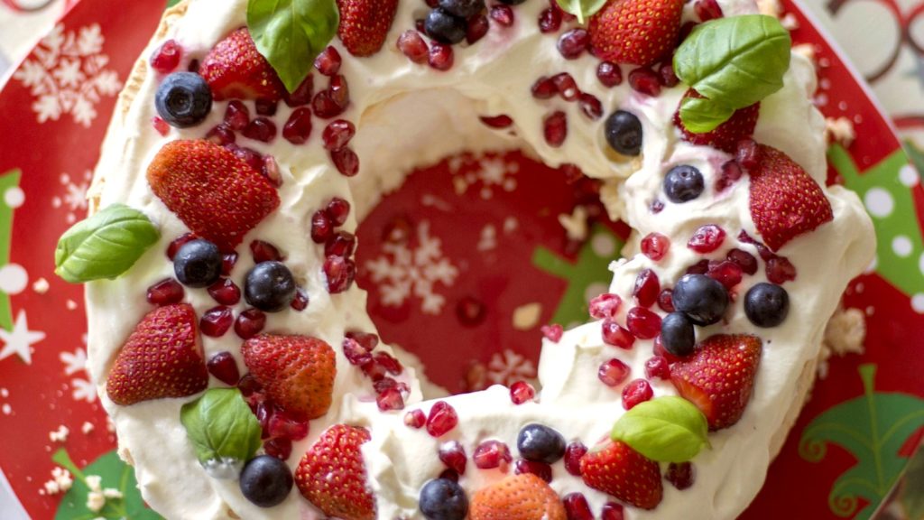 Pavlova with strawberries, pomegranates, and blueberries.