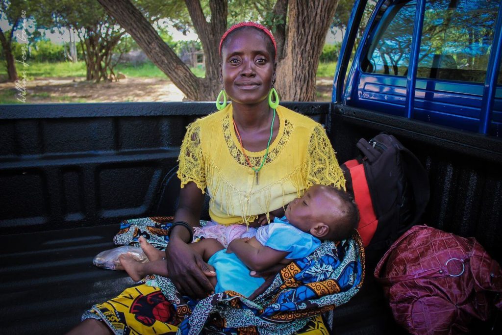 African woman wearing colourful clothing and holding her baby