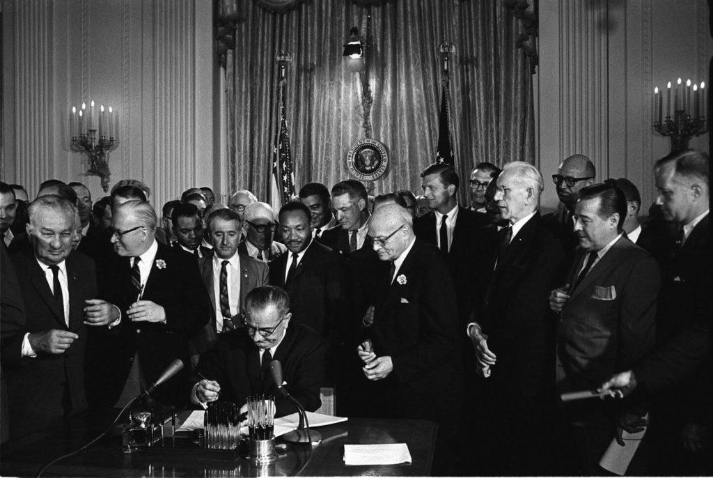 Martin Luther King Jr and the president signing the Civil Rights Act of 1964