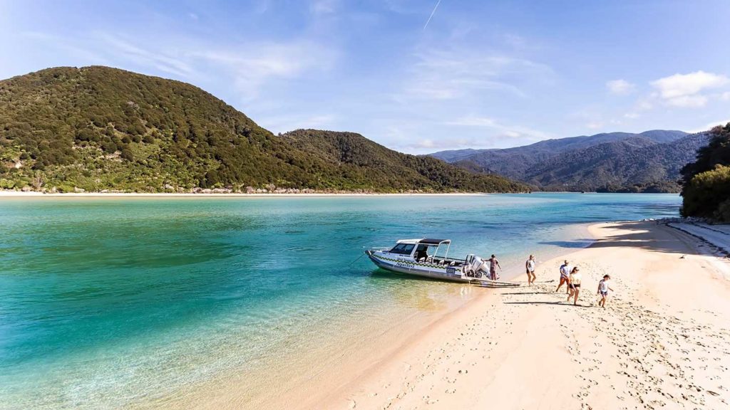 People disembarking a boat on a beach in New Zealand.